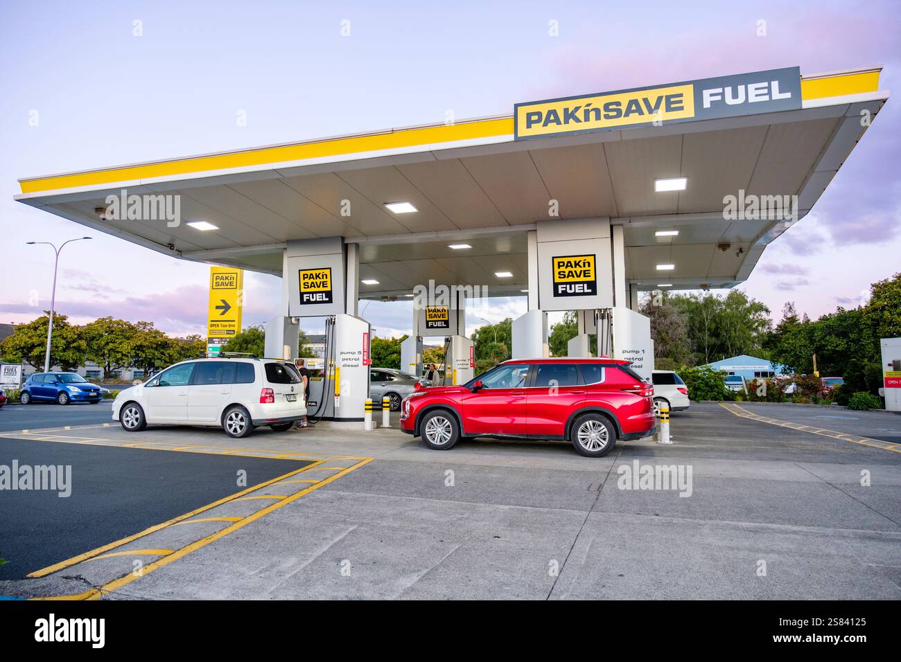 Pak n Save, Pak'nSave Tankstelle in Neuseeland bei Sonnenuntergang, wo Fahrzeuge unter einem hell beleuchteten Dach an modernen Tankstellen betankt werden. Stockfoto