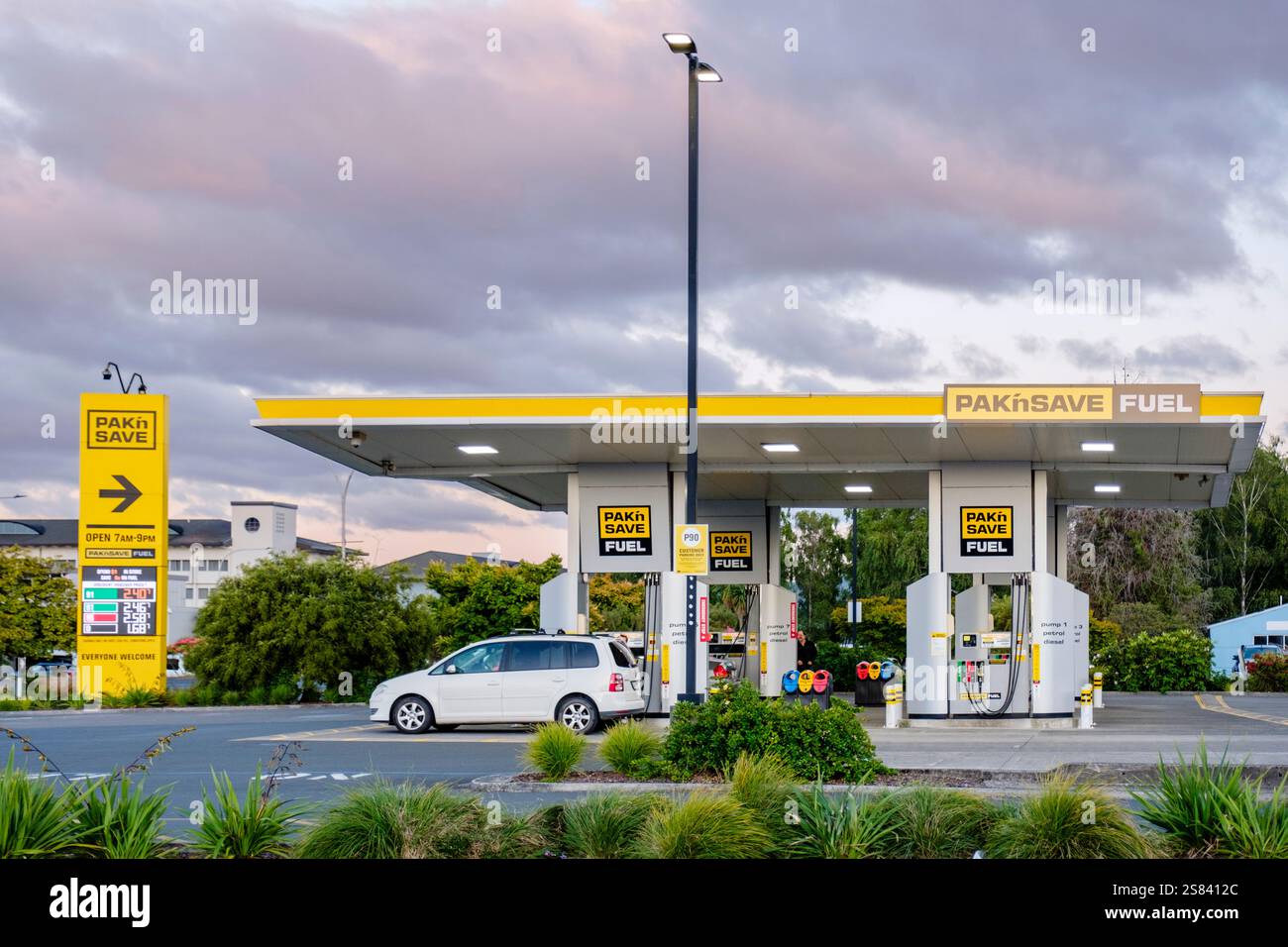 Pak n Save, Pak'nSave Tankstelle in Neuseeland bei Sonnenuntergang, wo Fahrzeuge unter einem hell beleuchteten Dach an modernen Tankstellen betankt werden. Stockfoto