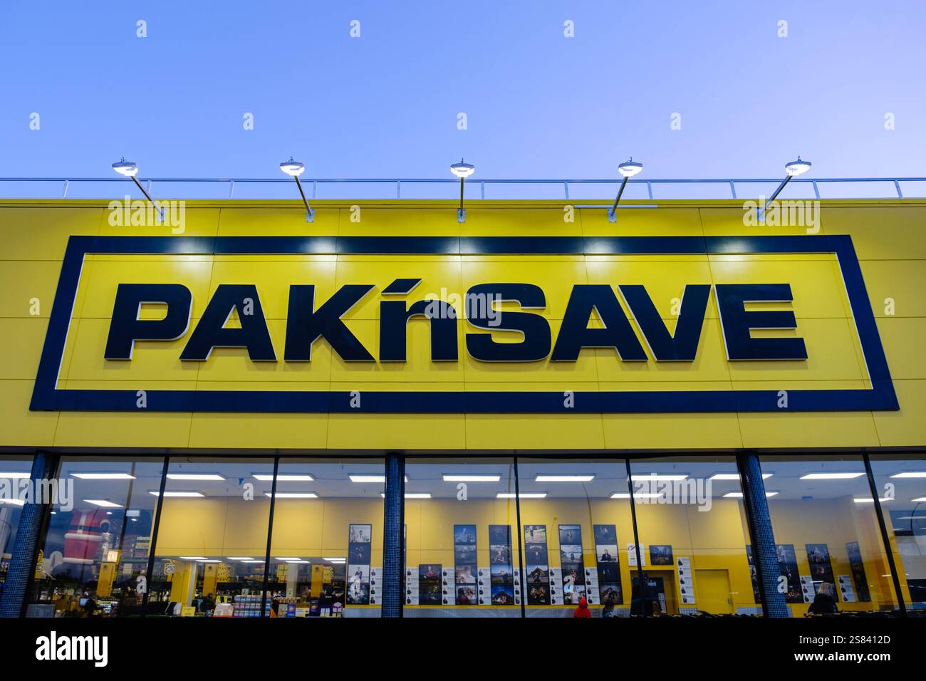 Pak'nSave Supermarkt in Neuseeland mit seiner ikonischen gelben Fassade, beleuchteten Schildern und modernem Design während der Dämmerung. Stockfoto