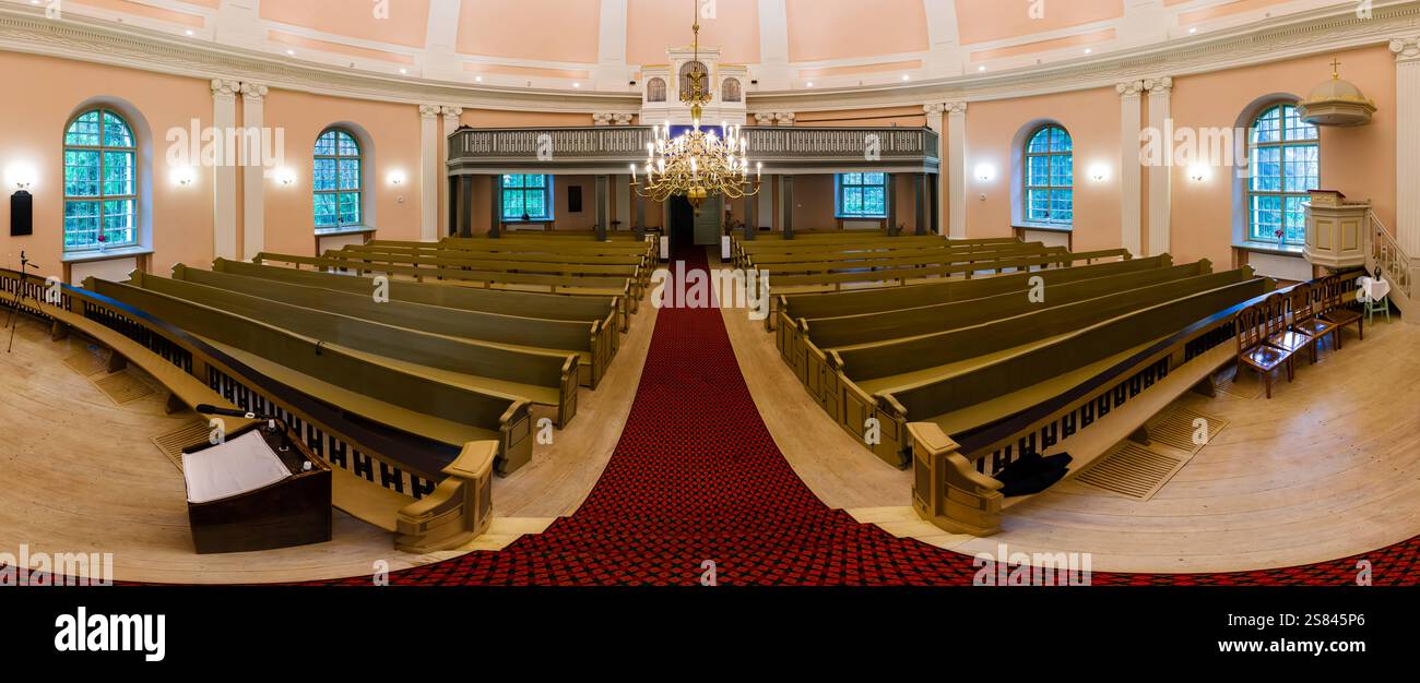 Symmetrisches Kircheninnere mit Holzbänken, rotem Teppich, kunstvollem Kronleuchter, Bogenfenstern, Balkonsitzen, und klassische architektonische Details Stockfoto