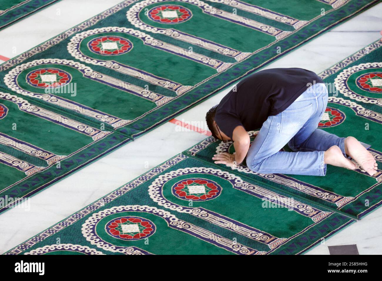 Al Akbar Surabaya Nationalmoschee, muslimischer Mann, der auf einem Teppich mit Bogendesign betet, der Richtung Mekka, Surabaya, Java, Indonesien zeigt Stockfoto