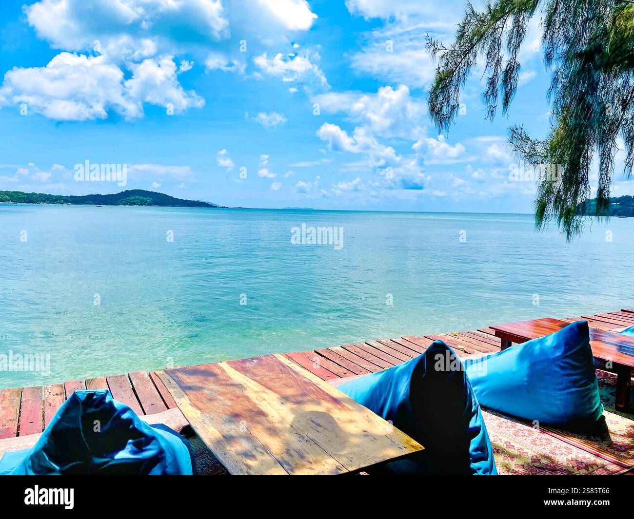 Eine ruhige und ruhige Umgebung mit einem Holztisch mit zwei weichen blauen Poufs auf beiden Seiten, die zum Entspannen einladen. Die Szene öffnet sich zu einem Awe-insp - Smartphone-aufgenommenes Stockfoto