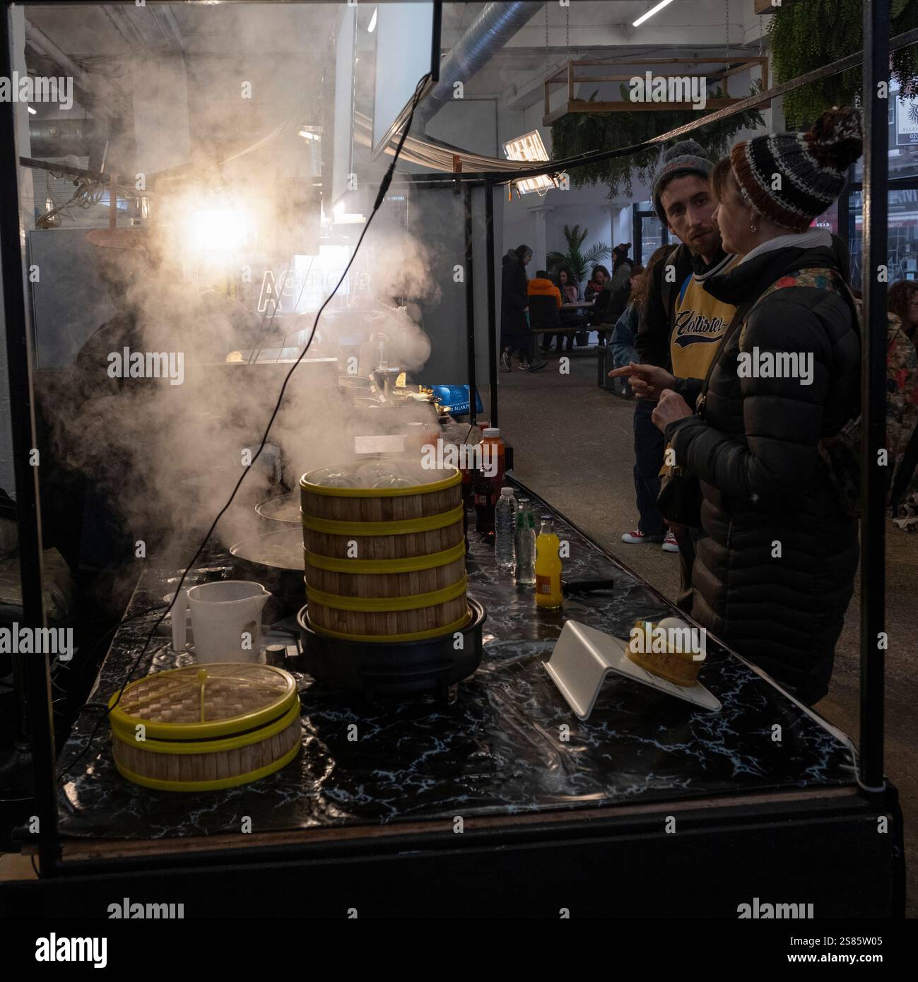 Leute, die in einem dampfenden, geschäftigen Brick Lane Street Food Outlet serviert werden Stockfoto