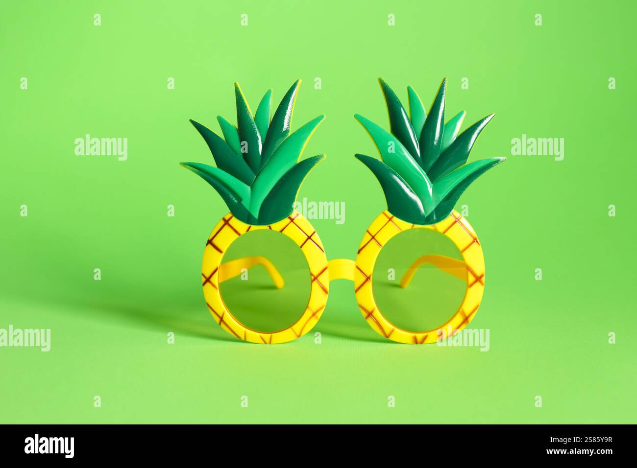 Kreative Sonnenbrille in Ananasform auf grünem Hintergrund Stockfoto