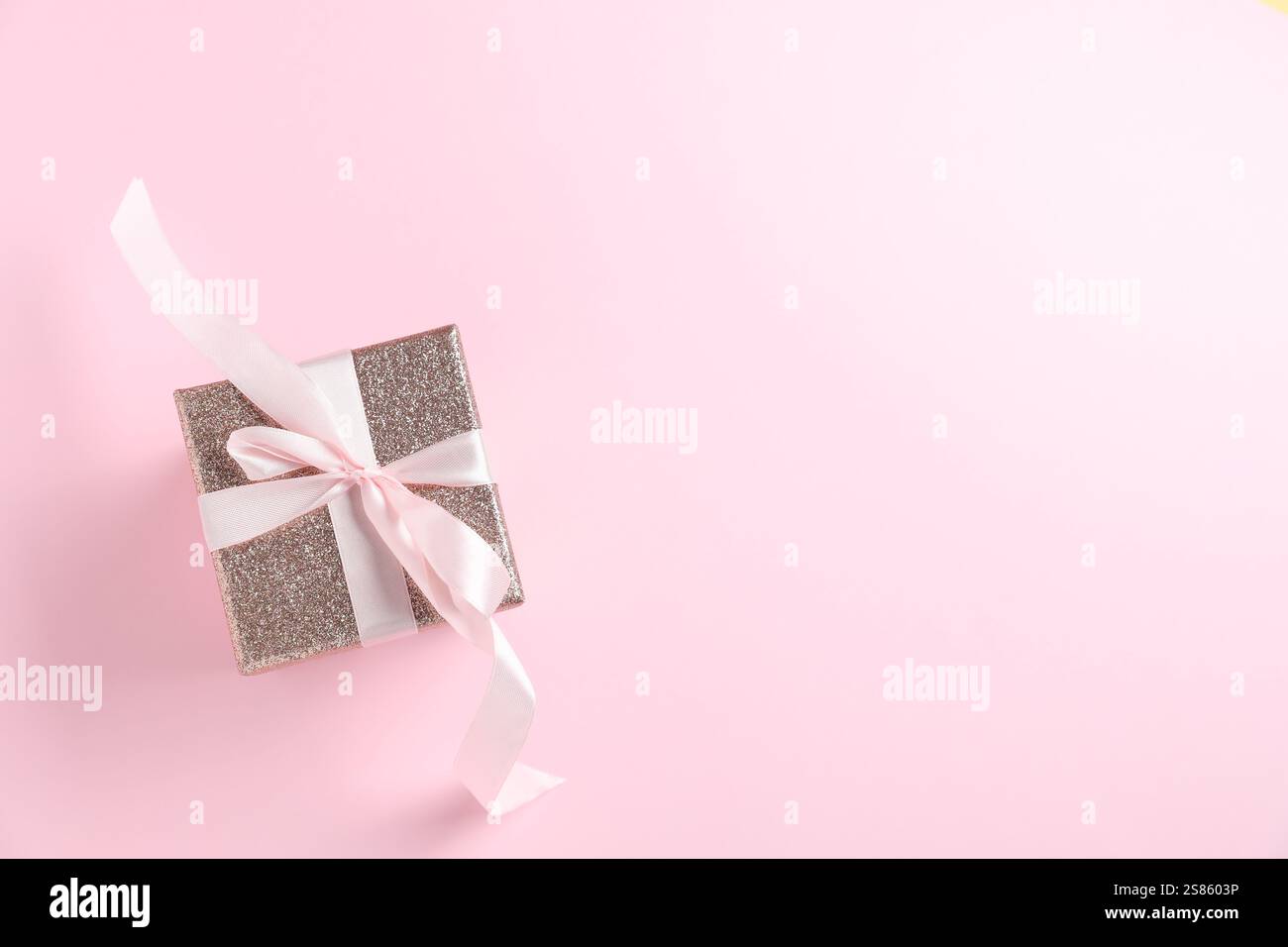 Romantisches Geschenk auf hellrosa Hintergrund, Draufsicht. Leerzeichen für Text Stockfoto