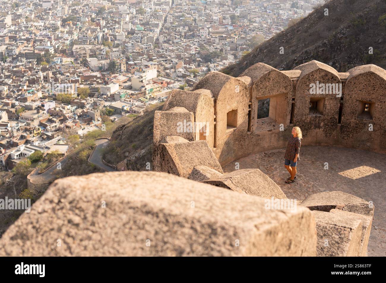 Junge blonde Frau, die an heißen sonnigen Tagen in Rajasthan, Indien, an den Wänden der rosa Stadt Jaipur spaziert. Stockfoto