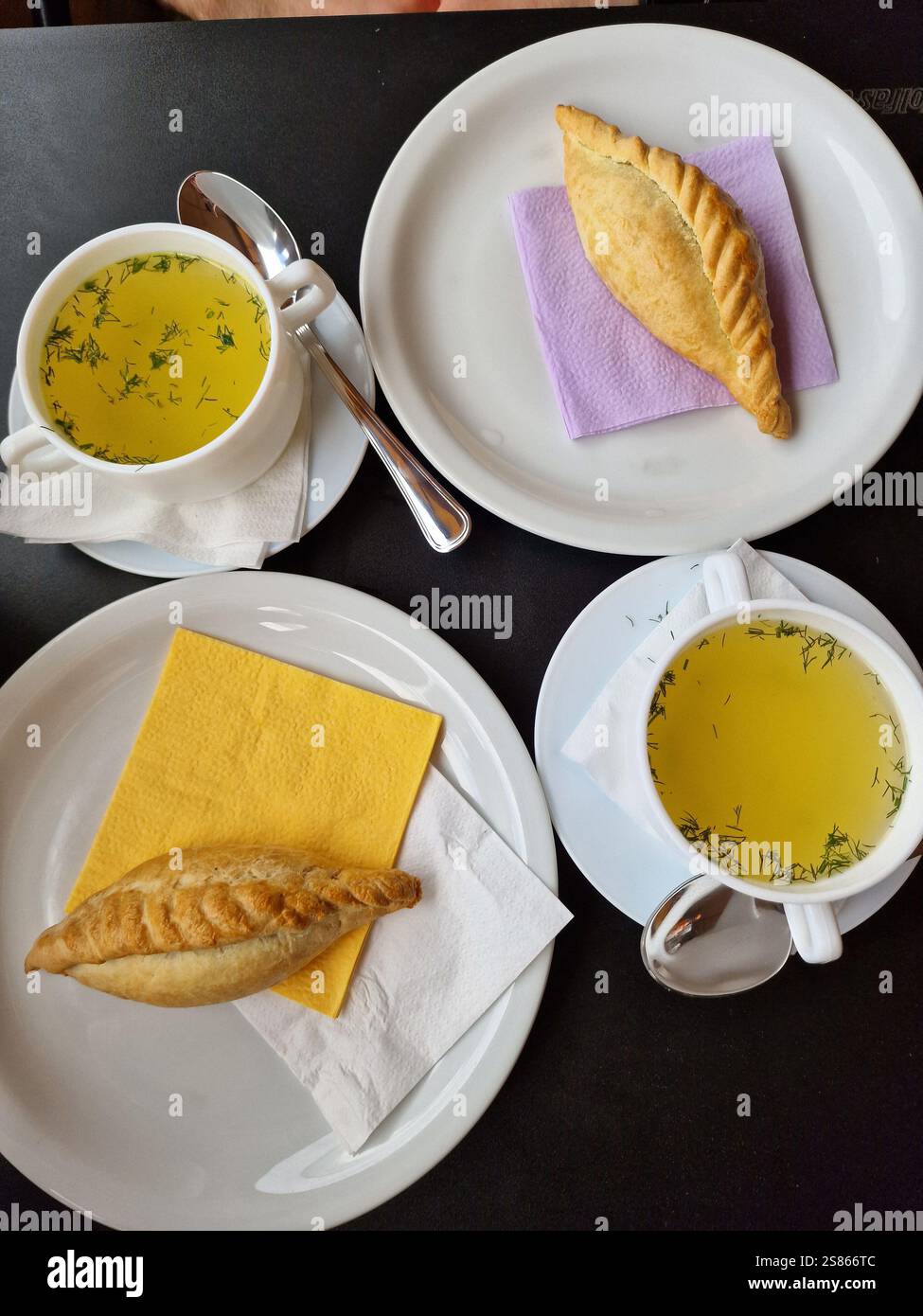 Traditionelles Gebäck gefüllt mit Hammelfleisch, serviert mit Hühnerbrühe auf dunklem Holzhintergrund. Kibinai, Kybyn, Kybynar, Chiburekki, Litauen Stockfoto
