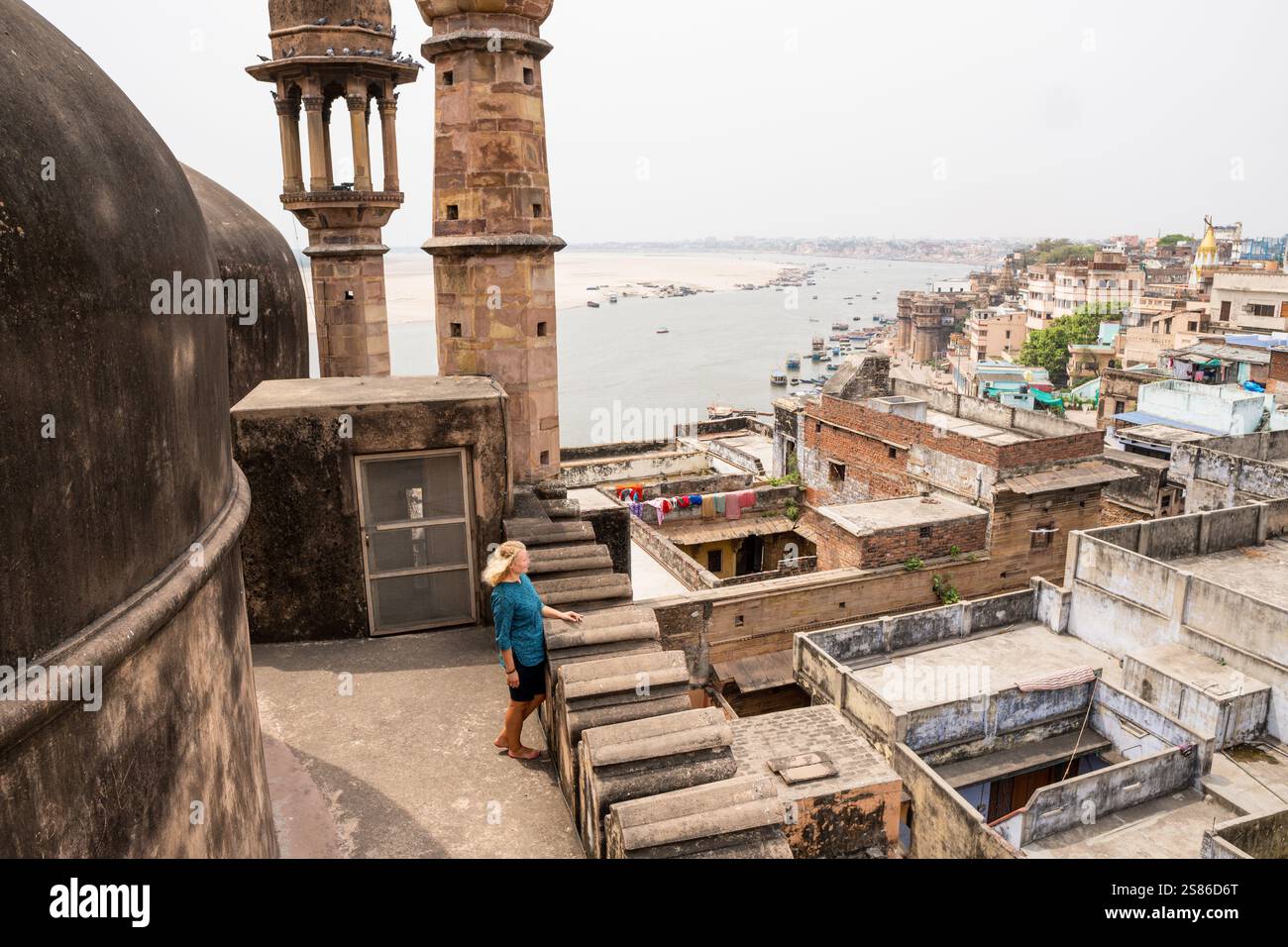 Junge Frau auf dem Dach der Moschee mit Blick auf die Altstadt von Varanasi und den Fluss Ganges in Uttar Pradesh, Indien. Stockfoto