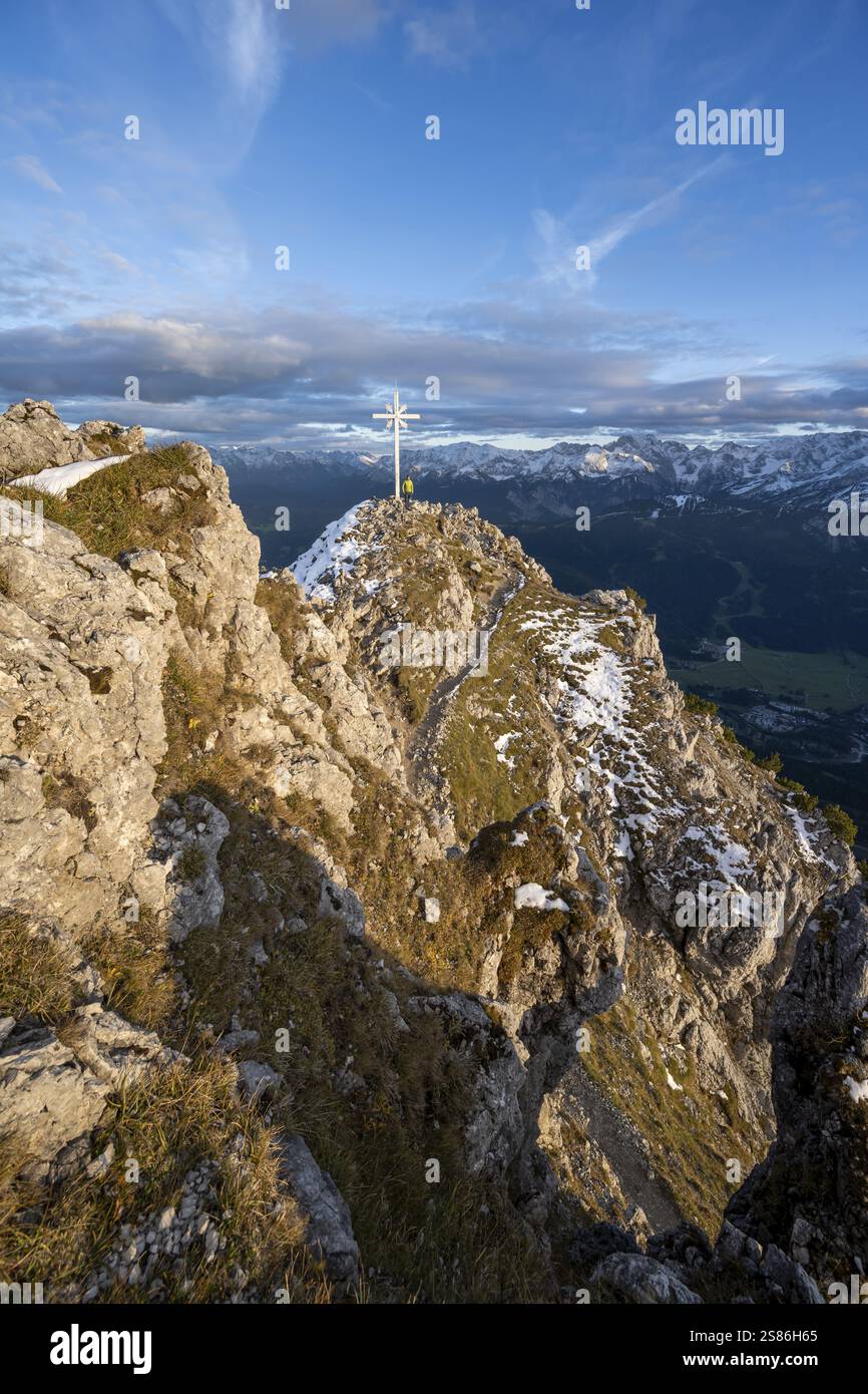 Bergsteiger auf dem Gipfel des Kramerspitzes mit Gipfelkreuz, bei Sonnenuntergang, im Herbst, Ammergauer Alpen, im Herbst, Bayerische Alpen, Bayern, Deutschland, Europ Stockfoto