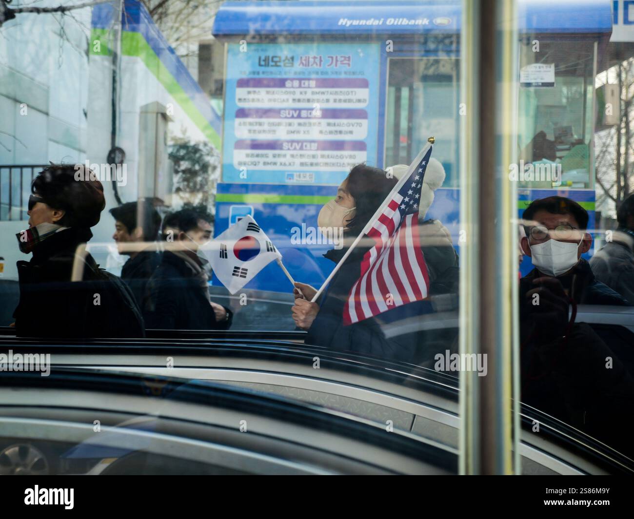 Seoul, Südkorea. Januar 2025. Eine Unterstützerin des aufgehobenen südkoreanischen Präsidenten Yoon Suk Yeol trägt koreanische und amerikanische Flaggen, als sie am Dienstag, den 21. Januar 2025, eine U-Bahn-Station in der Nähe des Verfassungsgerichts in Seoul verlässt. Yoon nahm an einem Amtsenthebungsverfahren wegen seiner Kriegserklärung Teil. Foto: Thomas Maresca/UPI Credit: UPI/Alamy Live News Stockfoto Seoul, Südkorea. Januar 2025. Eine Unterstützerin des aufgehobenen südkoreanischen Präsidenten Yoon Suk Yeol trägt koreanische und amerikanische Flaggen, als sie am Dienstag, den 21. Januar 2025, eine U-Bahn-Station in der Nähe des Verfassungsgerichts in Seoul verlässt. Yoon nahm an einem Amtsenthebungsverfahren wegen seiner Kriegserklärung Teil. Foto: Thomas Maresca/UPI Credit: UPI/Alamy Live News Stockfoto