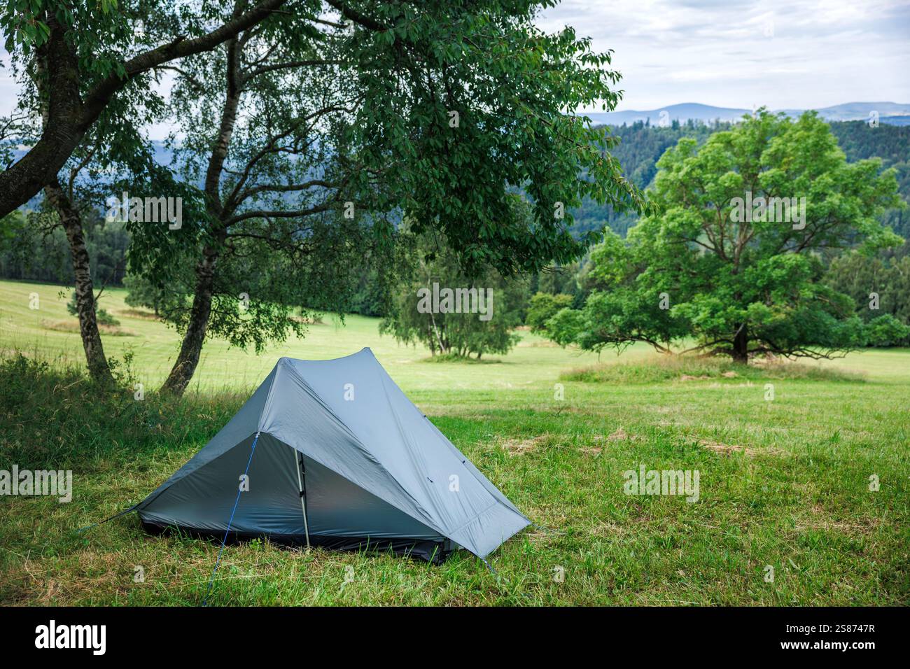 Camping auf einer Wiese in den Bergen. Ultraleichtes Zelt für Alleinwanderungen. Abenteuer in der Natur Stockfoto