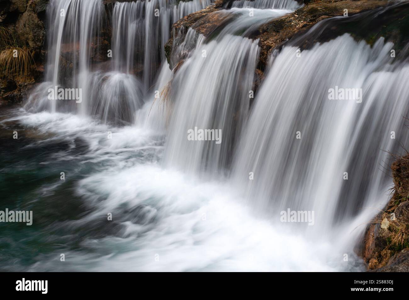 Faszinierender Wasserfall, der sich über felsiges Gelände zieht, mit seidenglatten Wasserläufen, die eine ruhige und ruhige Naturszene schaffen, perfekt für die Landschaft Stockfoto
