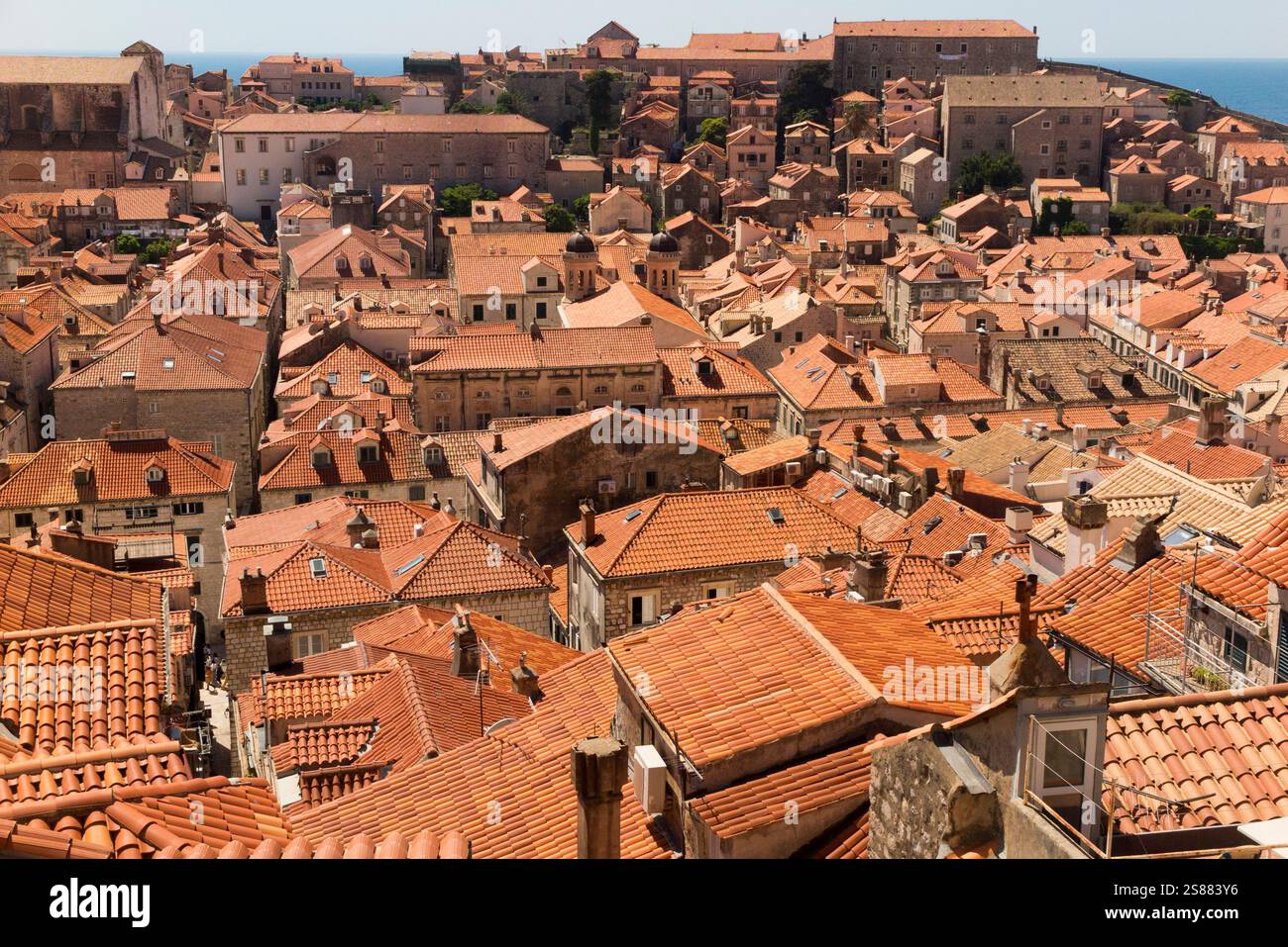 Blick von der historischen Stadtmauer über die Ziegeldächer der Gebäude in der ummauerten Altstadt von Dubrovnik in Richtung Adria. Kroatien. Sonniger Tag und blauer Himmel. (138) Stockfoto