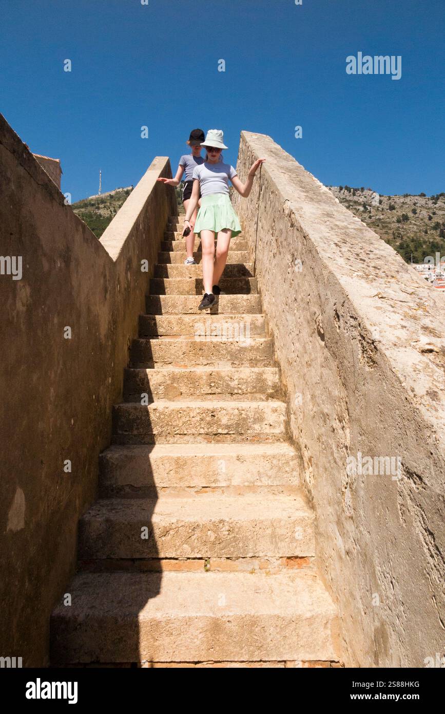 Kinder/Kinder klettern Steintreppen/Treppen auf der historischen Stadtmauer Wanderroute in der ummauerten Altstadt von Dubrovnik. Kroatien. Sonniger Tag und blauer Himmel. (138) Stockfoto