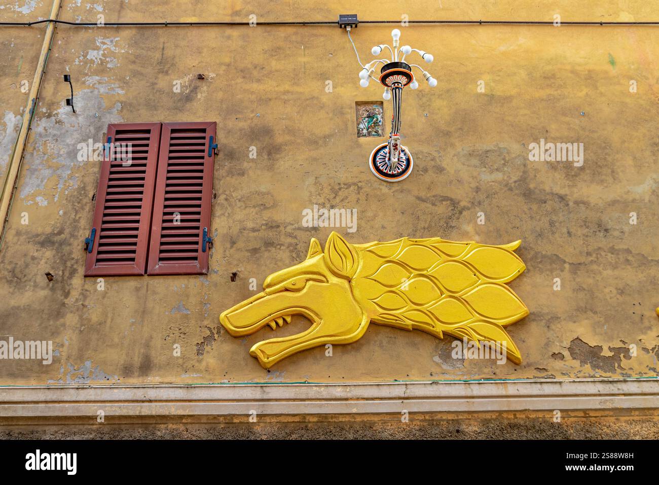 Eine Wandtafel mit dem Kopf einer Wolfsfrau, dem Symbol der Contrada della Lupa an einer Wand an der Via Pian D'Ovile in Siena, Italien Stockfoto