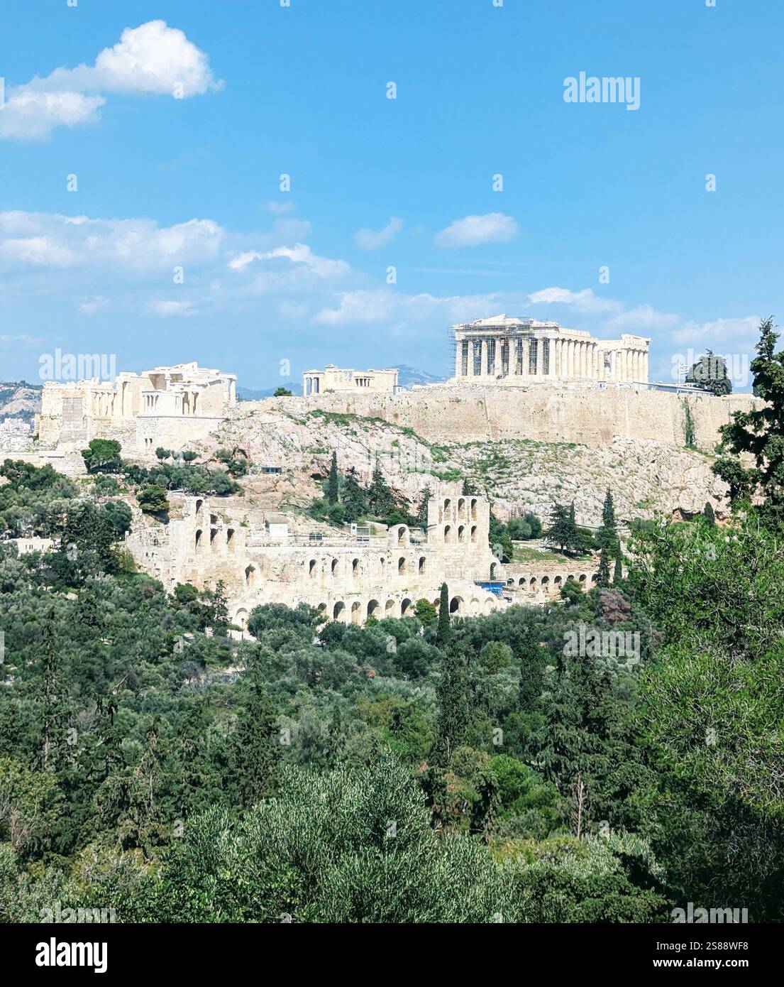 Ein atemberaubender Blick auf die Akropolis von Athen, mit dem Parthenon hoch über dem üppigen Grün und alten Ruinen darunter. Stockfoto