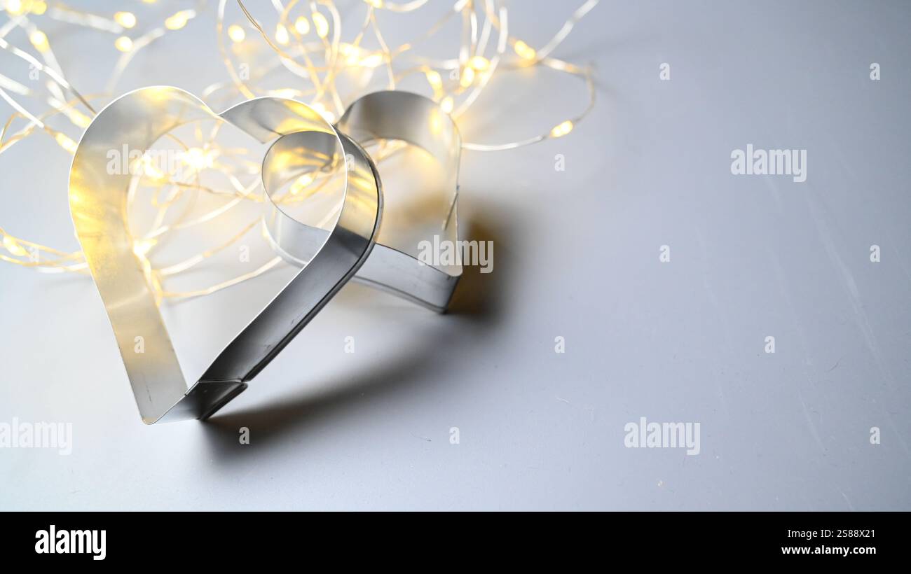 Weihnachtsstimmung mit zwei Herzpaaren als Keksschneider und Glitzer-Bokeh. Stockfoto