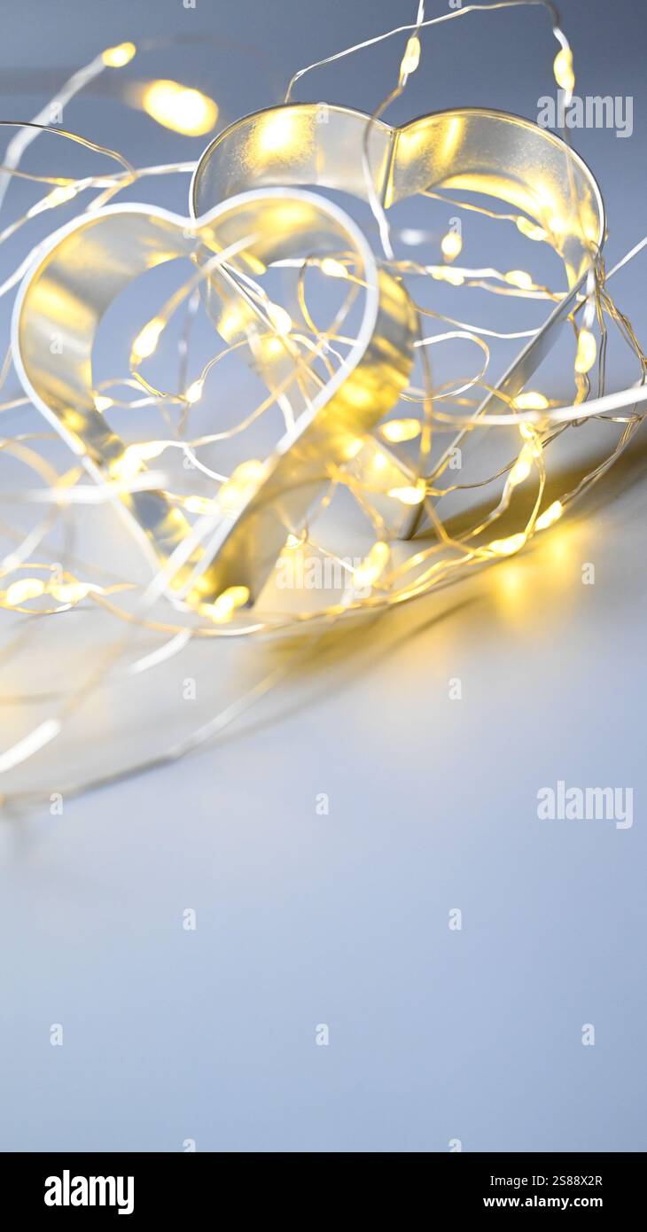 Weihnachtsstimmung mit zwei Herzpaaren als Keksschneider und Glitzer-Bokeh. Stockfoto