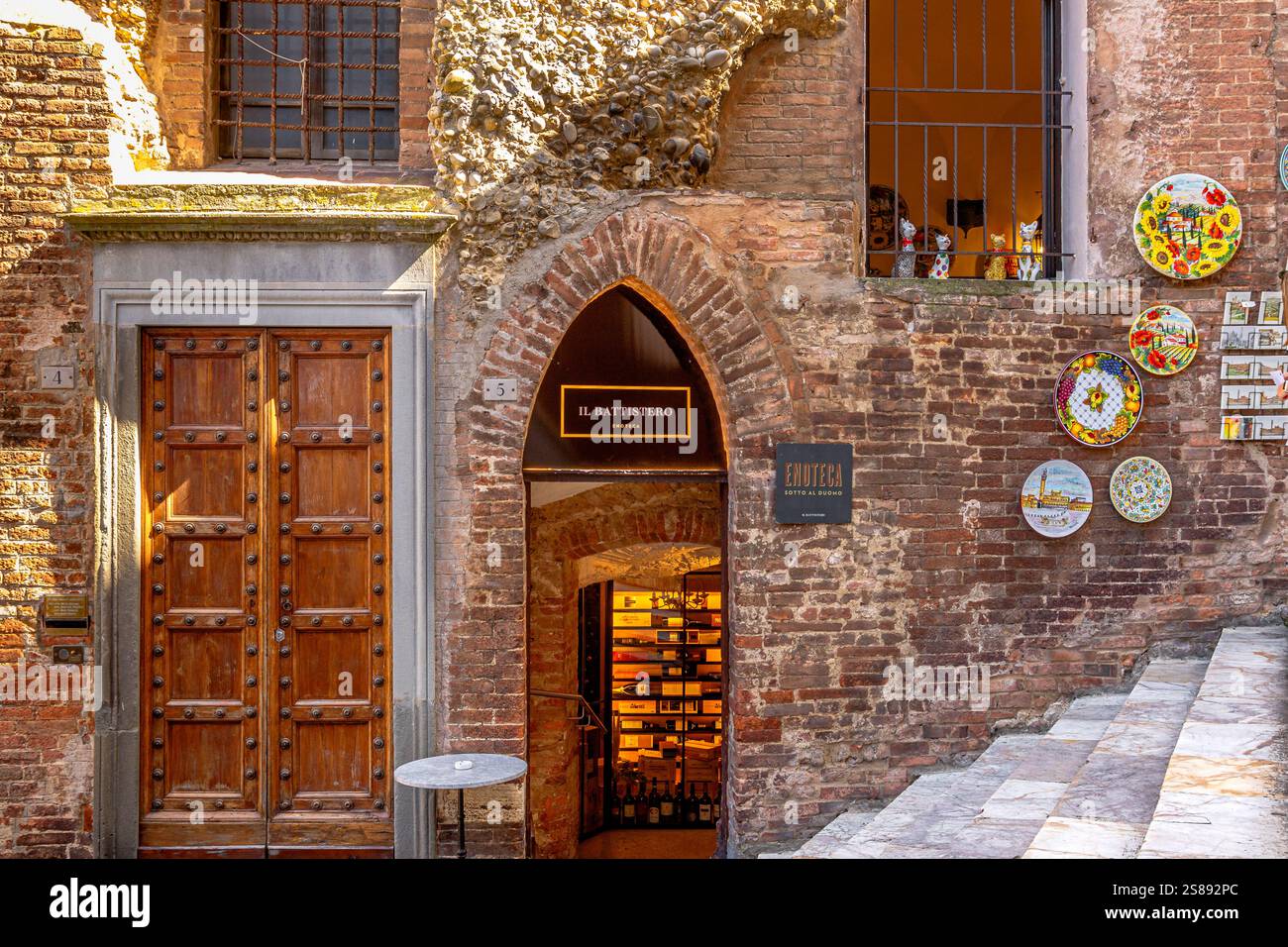 Der bogenförmige Eingang zur Enoteca Sotto al Duomo, einer Weinbar und Weinhändlern auf der Piazza San Giovanni, Siena, Italien Stockfoto