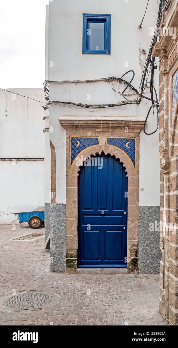 Die farbenfrohe blaue Tür, die von komplizierten Fliesendetails eingerahmt wird, unterstreicht Essaouiras einzigartige Architektur und den künstlerischen Geist in Marokko. Stockfoto