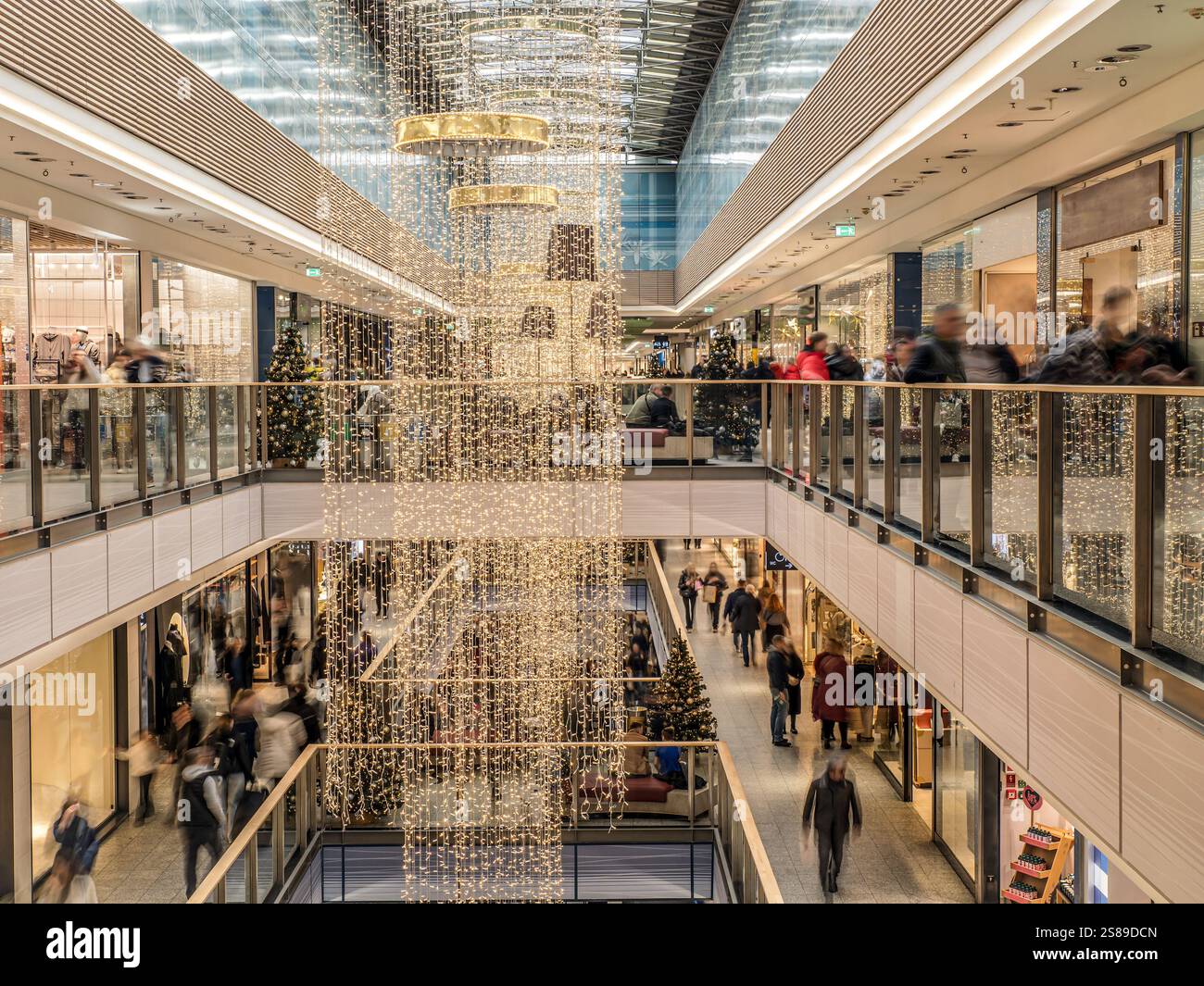 Ein belebtes Einkaufszentrum mit Weihnachtsbeleuchtung und Dekoration, gefüllt mit Kunden, die das festliche Ambiente genießen und die Vielfalt der Gäste erkunden Stockfoto