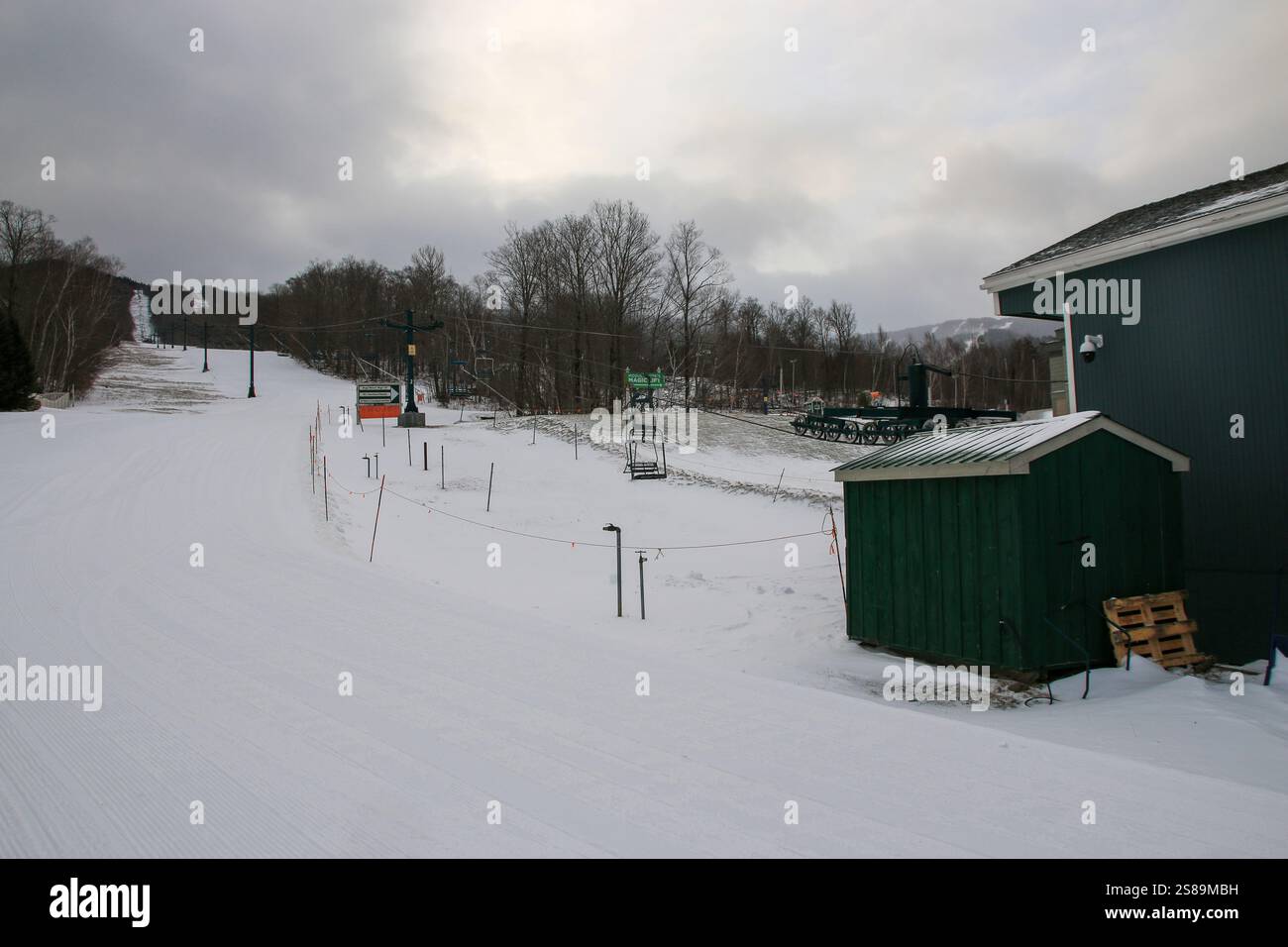 Die Winterlandschaft bietet eine ruhige Skipiste mit leerem Sessellift und eine Hütte mitten im Schnee. Stockfoto