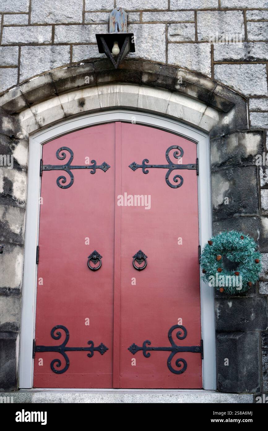 Weihnachtskranzdekoration und rote Holztür einer Kirche Stockfoto