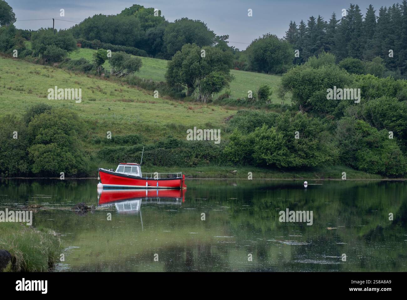 Ein kleines Boot liegt vor Anker in einer Bucht neben der Burrishoole Abbey. Stockfoto