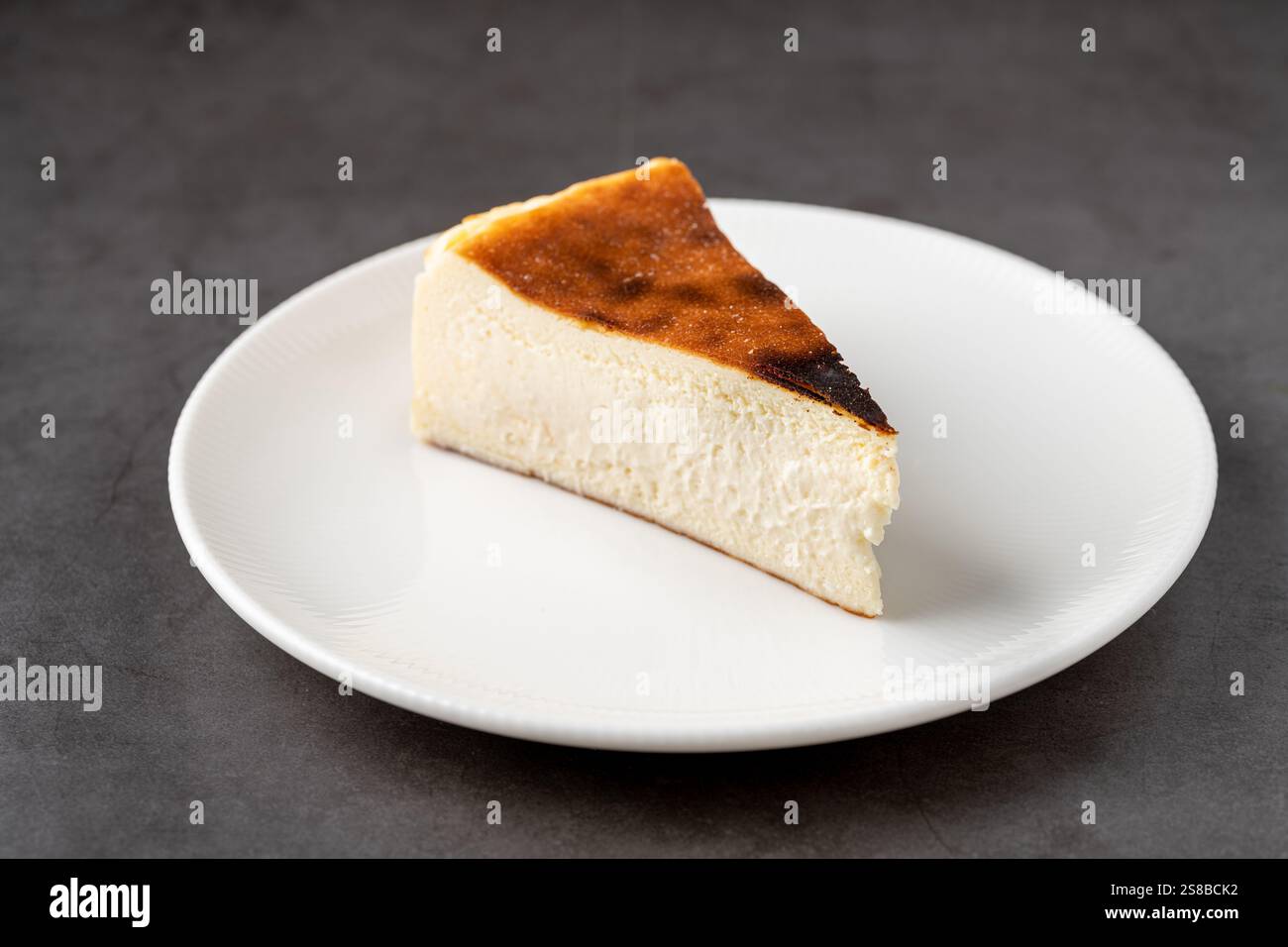 Beliebter spanischer Käsekuchen namens San Sebastian Käsekuchen auf einem Steintisch Stockfoto