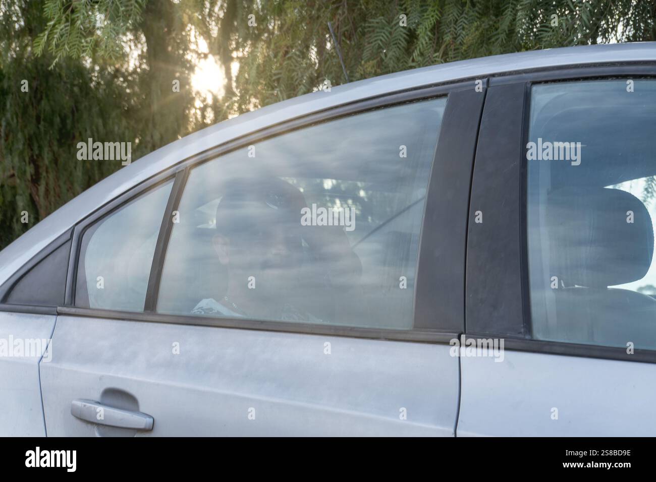 Das Auto parkte unter Bäumen und am späten Nachmittag strahlte das Sonnenlicht Stockfoto