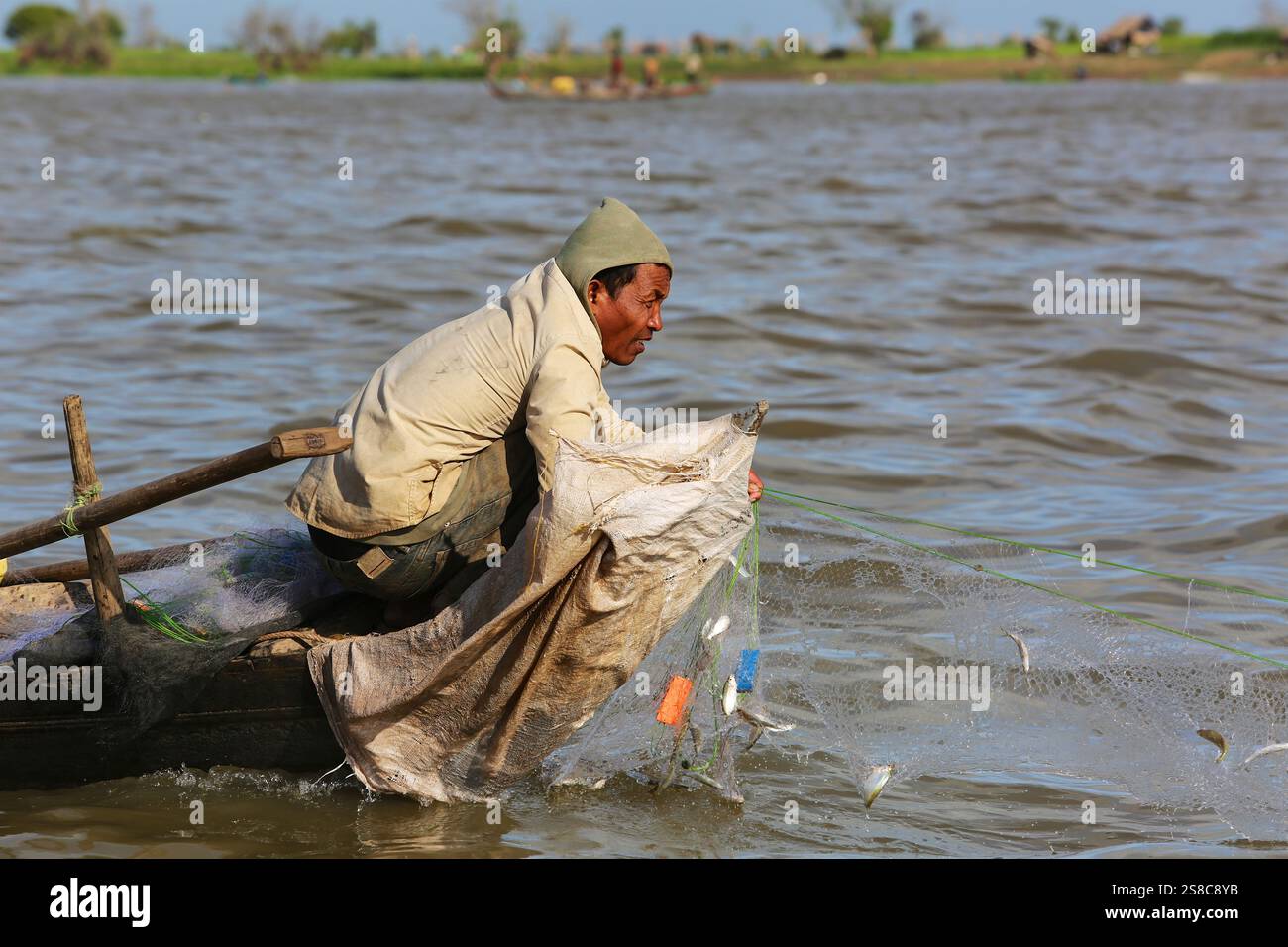 Ein Khmer-Fischer zieht seine Netze mit eingeschlossenen Süßwasserfischen aus den Gewässern des Tonle SAP Flusses, der den See mit dem Mekong in Kambodscha verbindet Stockfoto Ein Khmer-Fischer zieht seine Netze mit eingeschlossenen Süßwasserfischen aus den Gewässern des Tonle SAP Flusses, der den See mit dem Mekong in Kambodscha verbindet Stockfoto