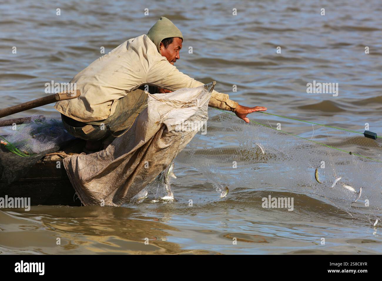 Ein Khmer-Fischer zieht seine Netze mit eingeschlossenen Süßwasserfischen aus den Gewässern des Tonle SAP Flusses, der den See mit dem Mekong in Kambodscha verbindet Stockfoto Ein Khmer-Fischer zieht seine Netze mit eingeschlossenen Süßwasserfischen aus den Gewässern des Tonle SAP Flusses, der den See mit dem Mekong in Kambodscha verbindet Stockfoto