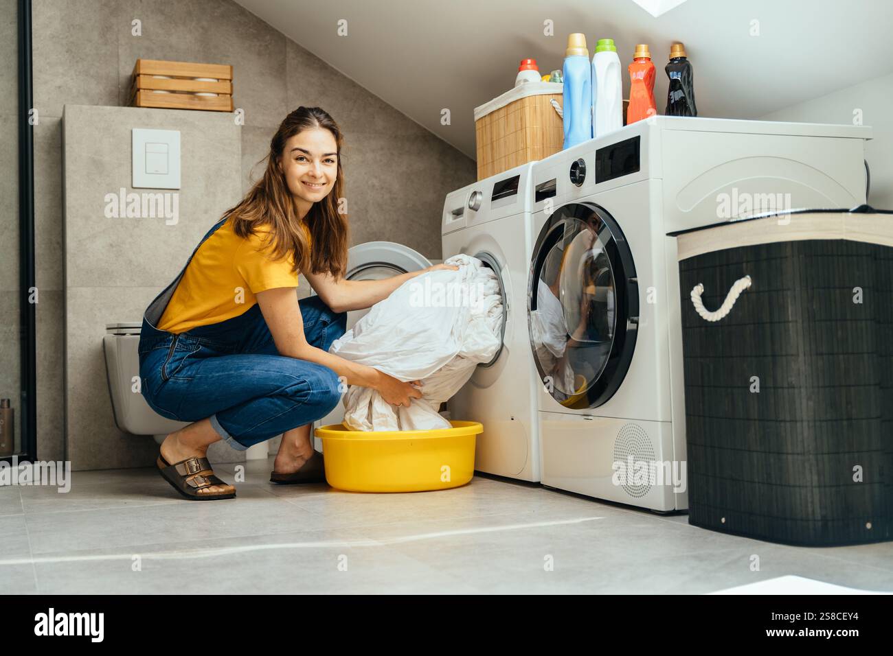 Junge Frau lächelt beim Waschen in modernen Wohnräumen Stockfoto