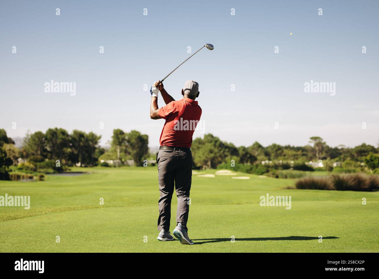 Man schwingt den Golfschläger in perfekter Follow-Through-Position während eines Annäherungsschlags an einem sonnigen Tag, der die Essenz von Fokus und Präzision im Golf einfängt Stockfoto
