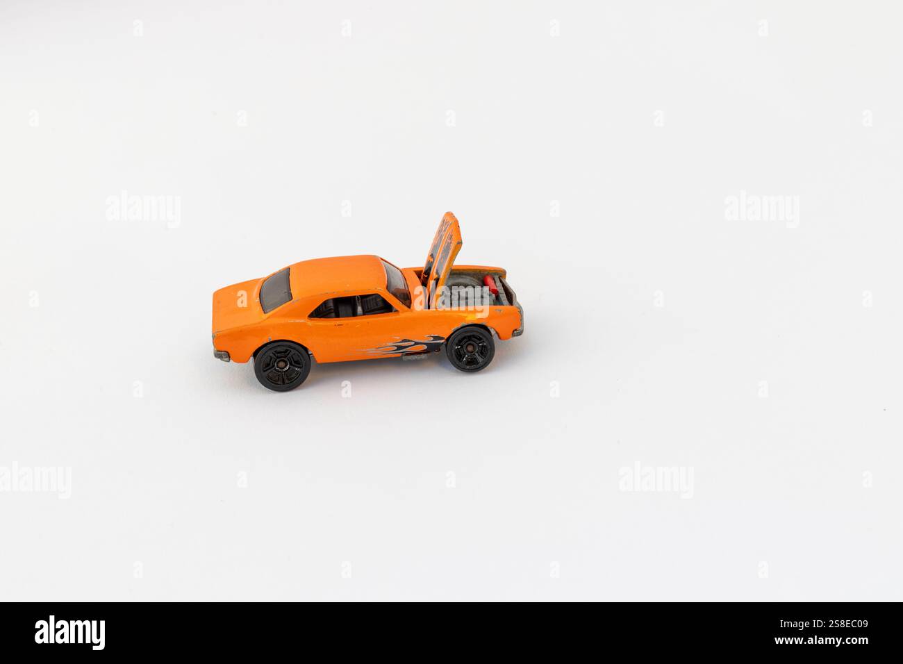 Orangefarbenes Spielzeugrennauto mit offener Haube auf weißem Hintergrund mit Kopierraum Stockfoto
