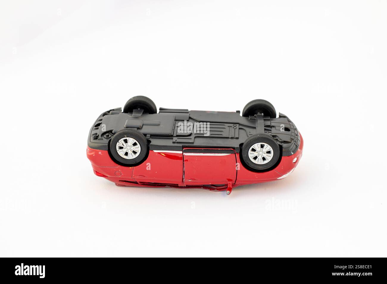 Wrackteile eines Toy Red Autos, das bei einem Verkehrsunfall kopfüber lag Stockfoto