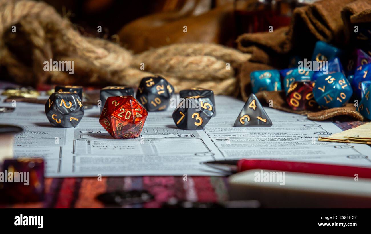Verlieren Sie die Tabletop-RPG-Würfel, einschließlich eines roten D20, auf Charakterbögen, umgeben von Spielfiguren und farbenfrohen Accessoires. Stockfoto
