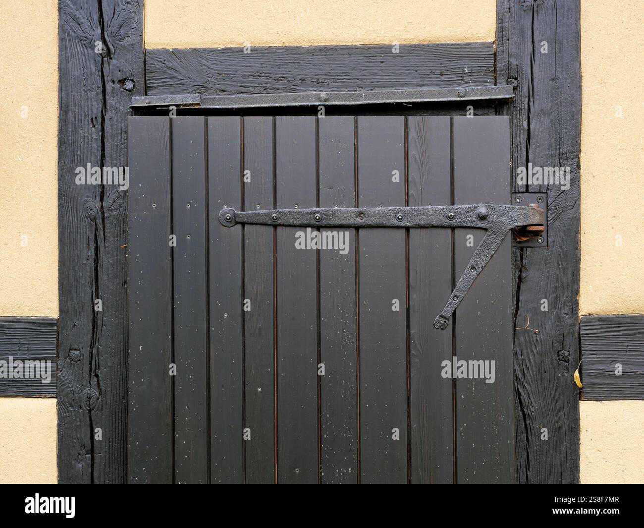 Holztür in einer Fachwerkscheune. Die Türbeschläge und die tiefe Holzmaserung verleihen dem Bild einen rustikalen Charme Stockfoto Holztür in einer Fachwerkscheune. Die Türbeschläge und die tiefe Holzmaserung verleihen dem Bild einen rustikalen Charme Stockfoto