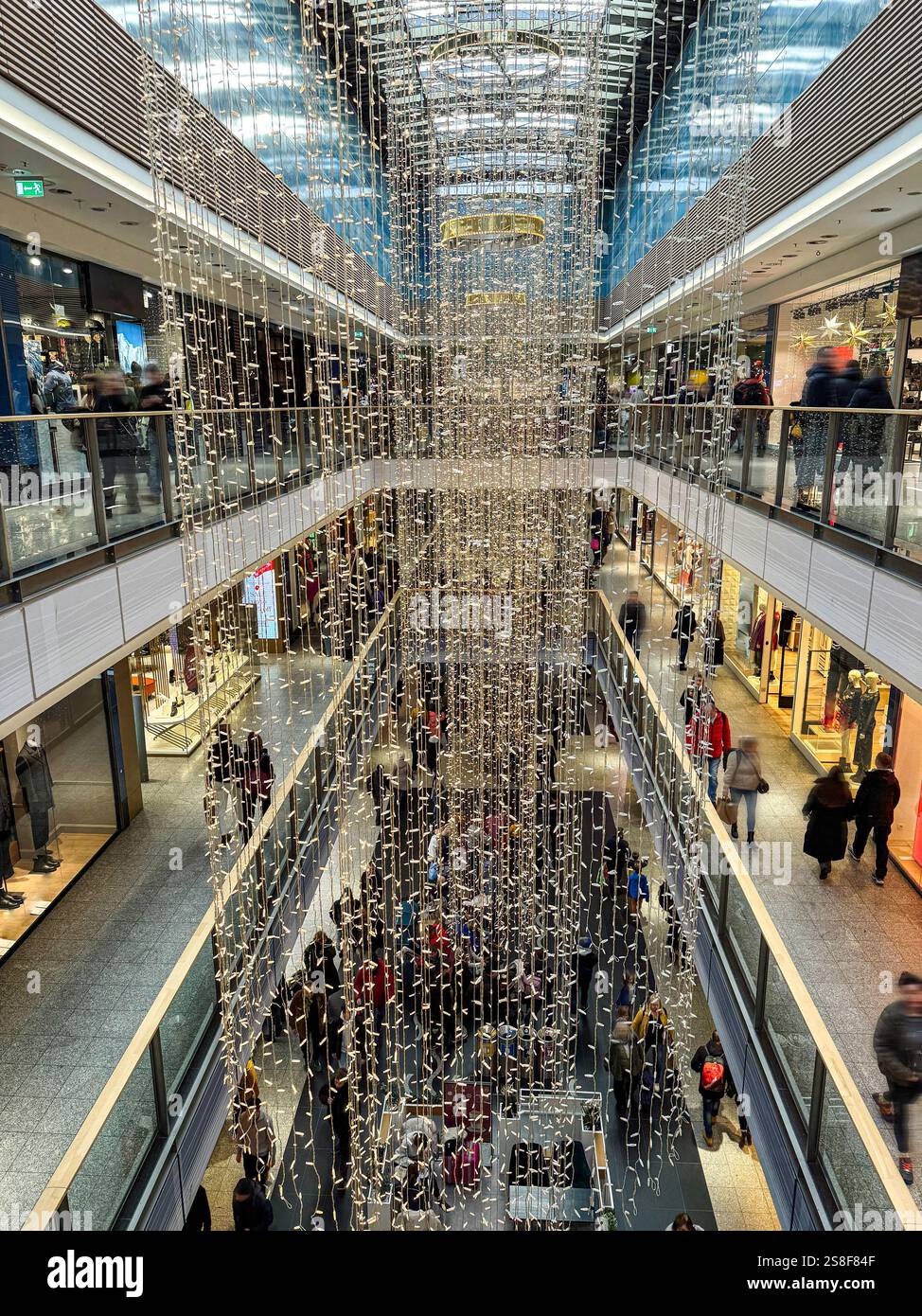 Ein belebtes Einkaufszentrum mit Weihnachtsbeleuchtung und Dekoration, gefüllt mit Kunden, die das festliche Ambiente genießen und die Vielfalt der Gäste erkunden Stockfoto