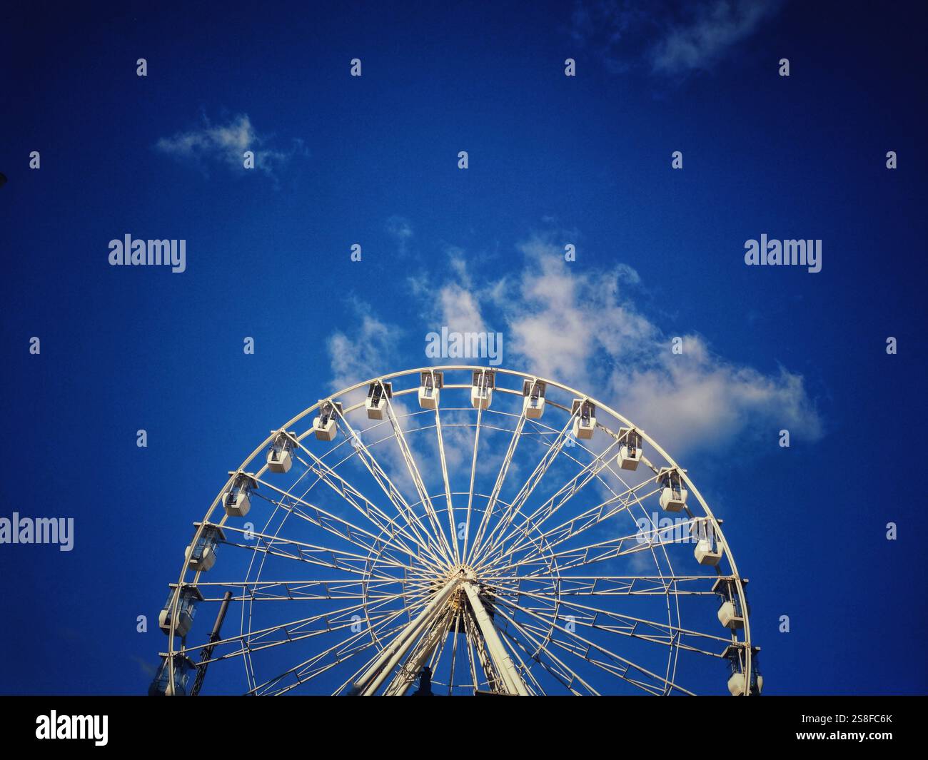 Großes Riesenrad vor einem hellblauen Himmel mit flauschigen weißen Wolken während des Tages - Smartphone-aufgenommenes Stockfoto