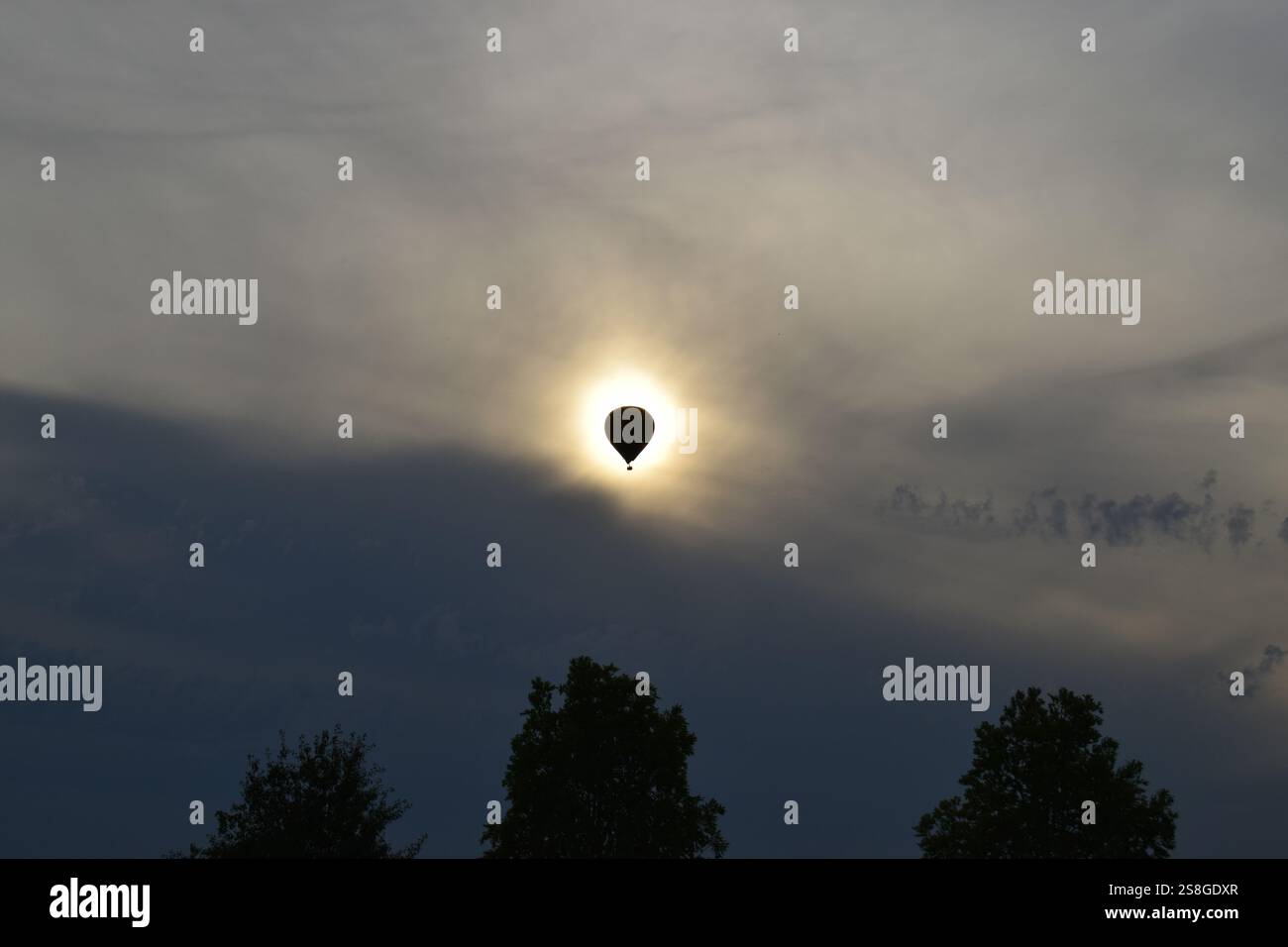 Eine atemberaubende Silhouette eines Heißluftballons, der vor der Sonne vorbeifährt und einen einzigartigen Effekt wie eine Sonnenfinsternis am Himmel erzeugt. Stockfoto