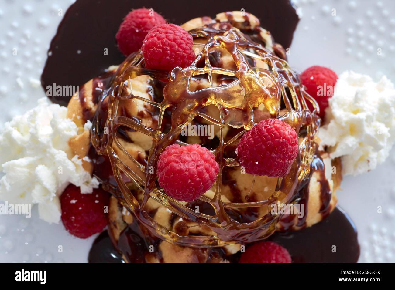 Elegantes Dessert mit Himbeeren, Schlagsahne und Schoko Drizzle Stockfoto