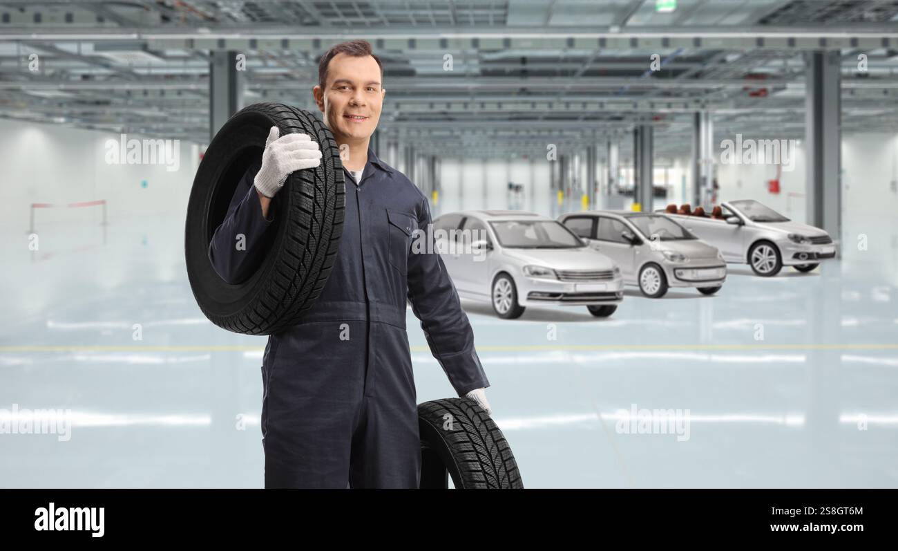 Autoreparaturarbeiter mit Reifen in einer Autogarage Stockfoto