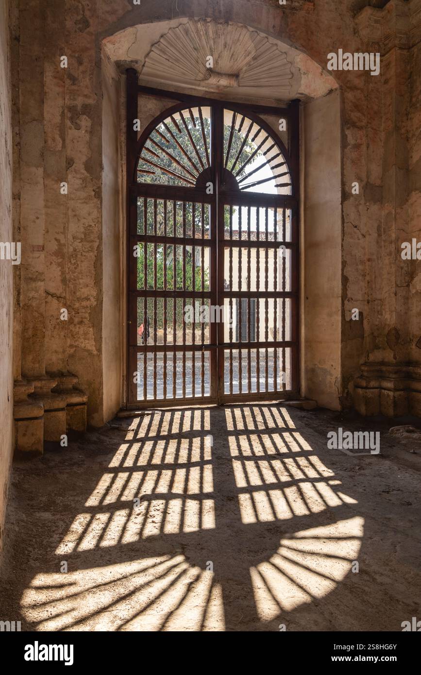 Antigua Guatemala, Sacatepequez, Guatemala. März 2024. Schatten und vergitterte Tür in den Ruinen der Kathedrale von Santiago. Stockfoto