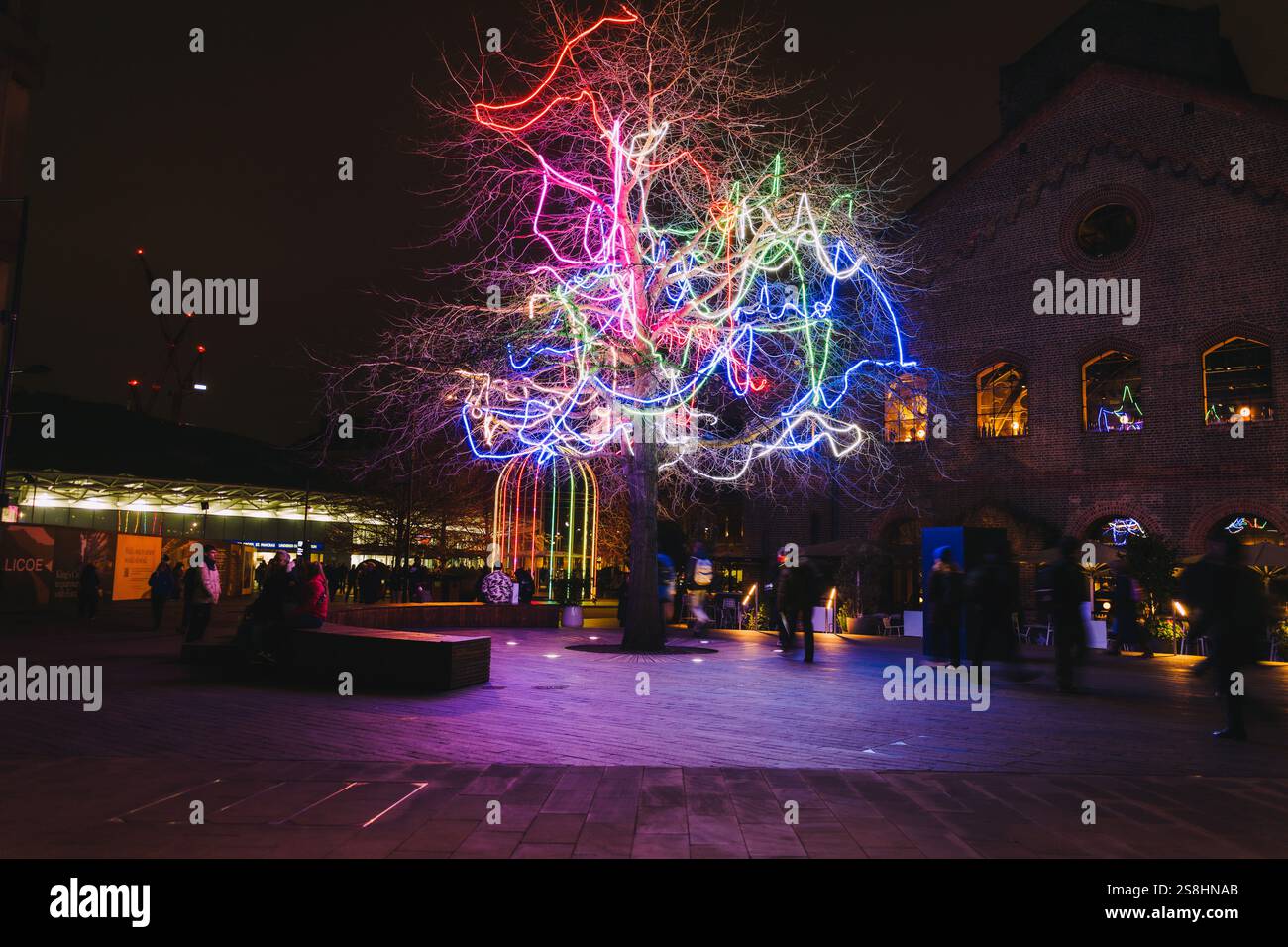 Beleuchtete Bauminstallation mit bunten Neonlichtern in einer nächtlichen urbanen Umgebung am Kings Cross Stockfoto