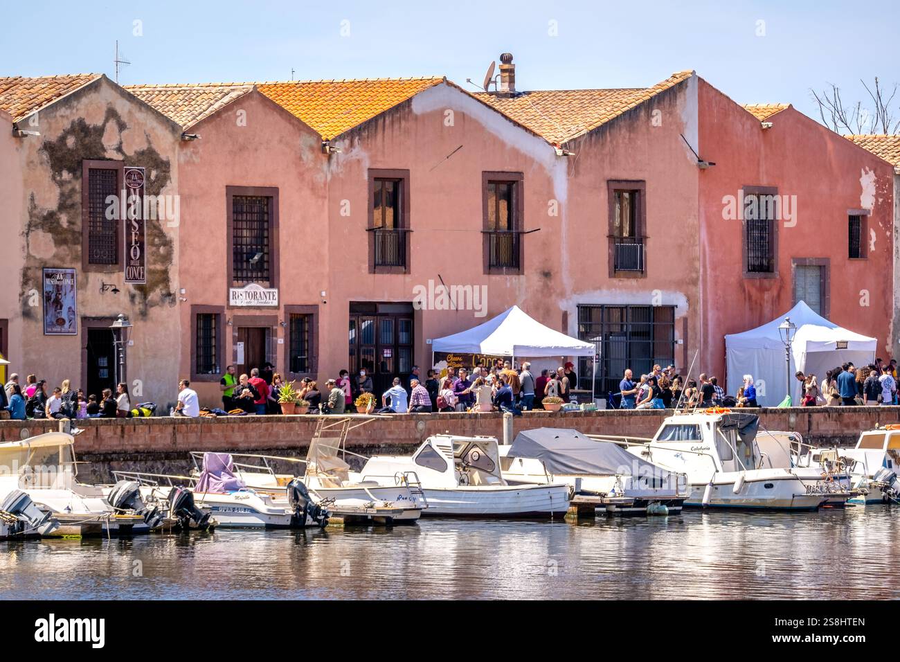 Boote im Fluss Temo und Häuser an der Promenade, Gäste in den Restaurants mit Catering im Freien, Bosa, Europa, Provinz Oristano, Italien Stockfoto