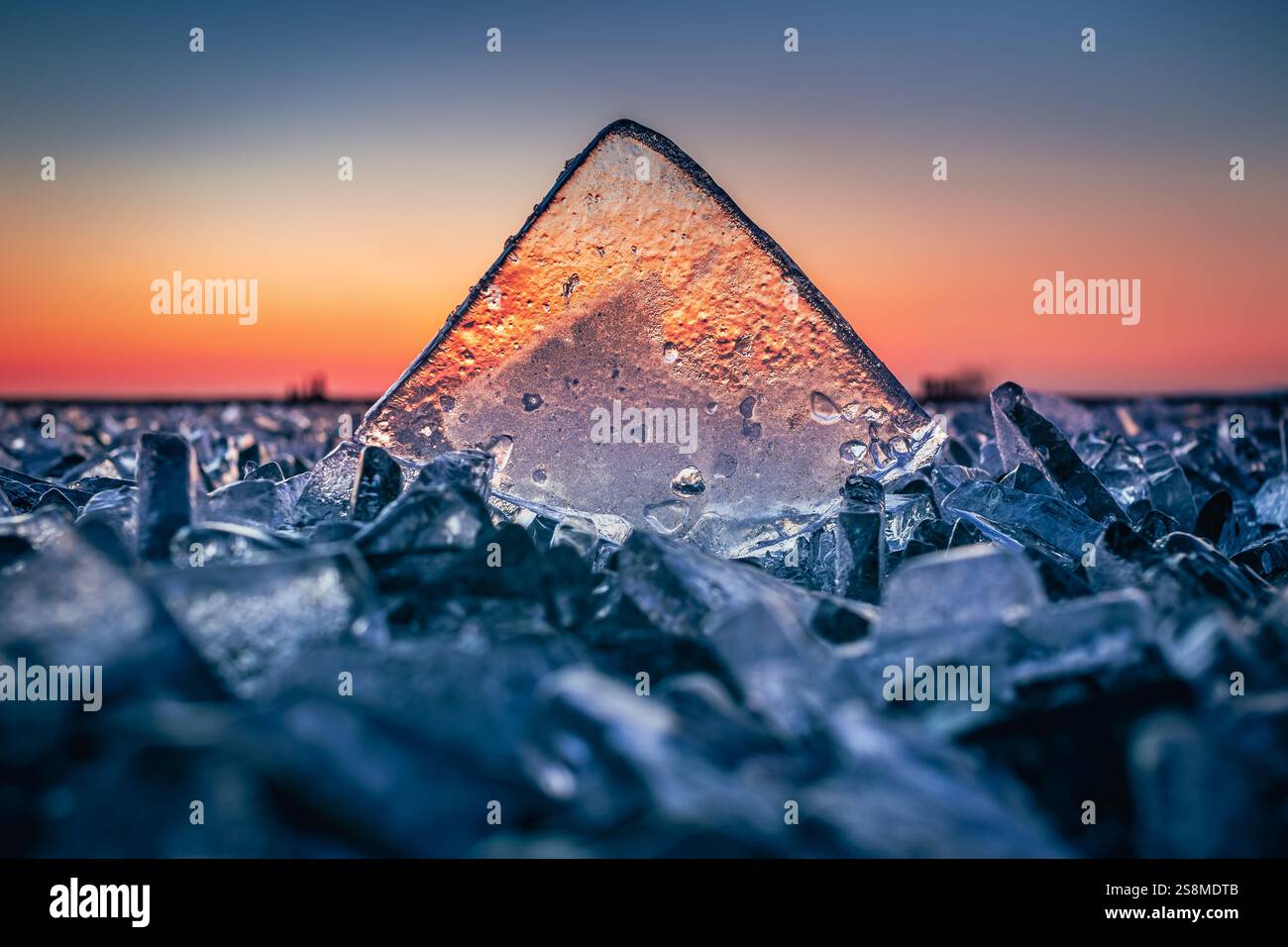 Fonyod, Ungarn – transparenter Eiswürfel auf dem gefrorenen Balaton an einem kalten Winternachmittag mit goldenen Sonnenuntergangslichtern Stockfoto