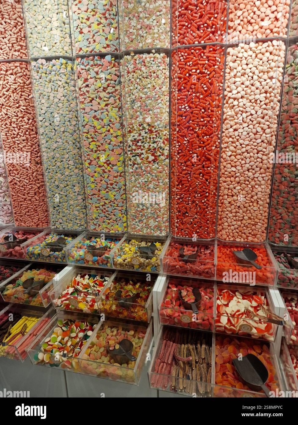 Farbenfrohe Auswahl an verschiedenen Bonbons, die in riesigen Glasbehältern präsentiert werden und eine Vielzahl von Formen und Aromen für ein süßes Erlebnis bieten Stockfoto