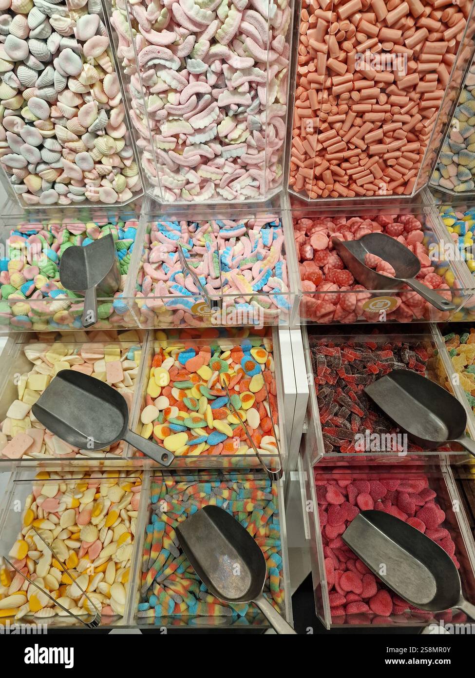 Farbenfrohe Auswahl an verschiedenen Bonbons, die in riesigen Glasbehältern präsentiert werden und eine Vielzahl von Formen und Aromen für ein süßes Erlebnis bieten Stockfoto