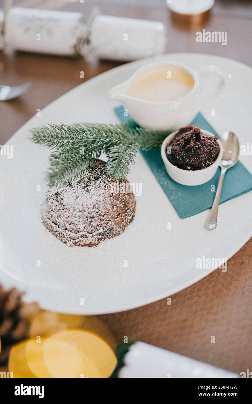 Ein Teller Dessert mit einem weißen Teller und einer blauen Serviette. Das Dessert ist ein Kuchen mit Puderzucker drauf Stockfoto